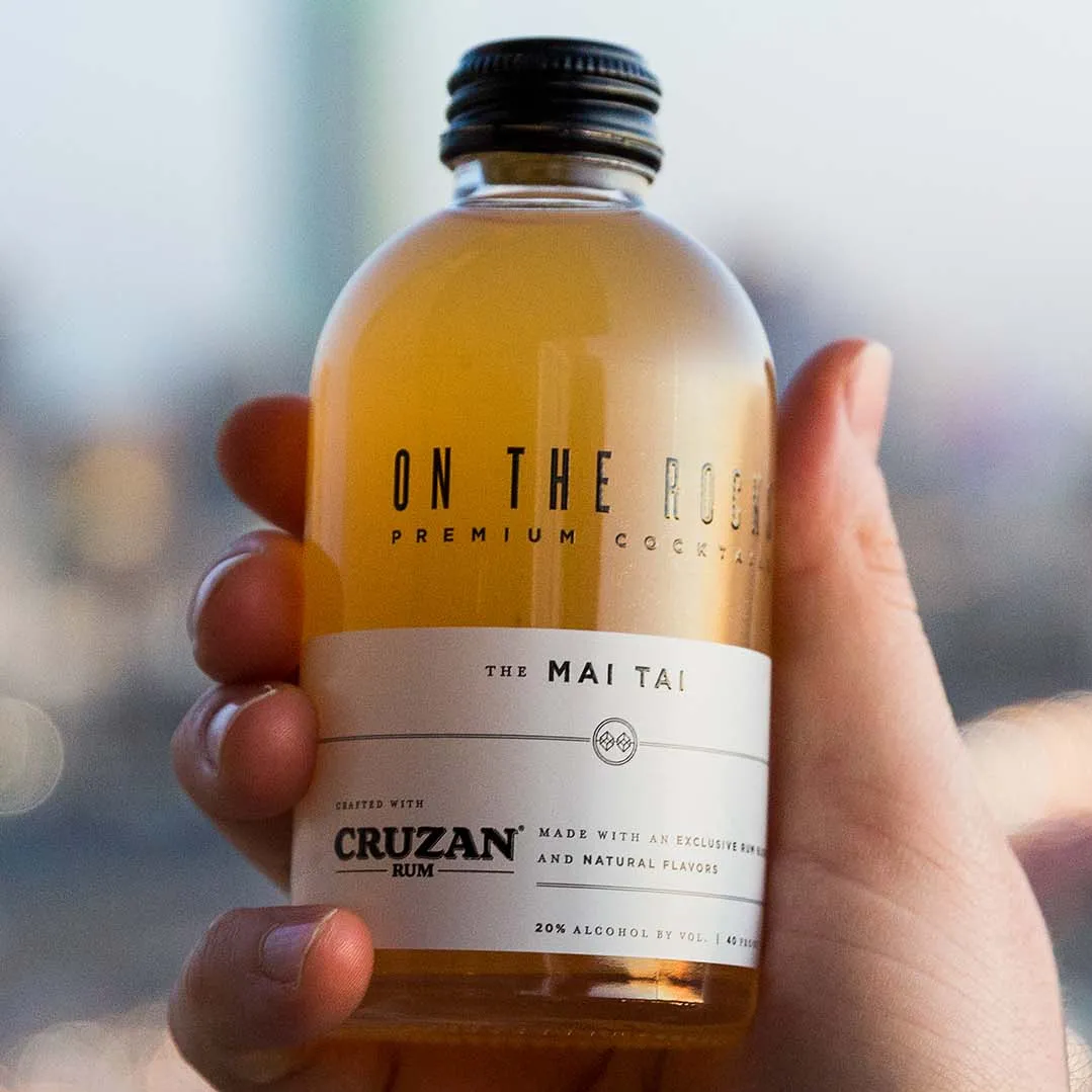 A hand holding a bottle of OTR Mai Tai cocktail