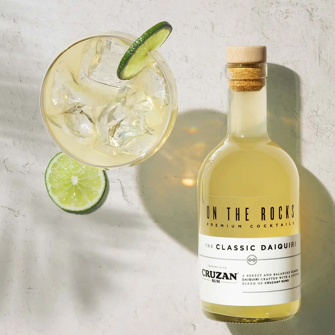 A bottle of OTR Daiquiri cocktail next to a drink served with lime