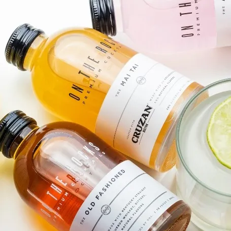 OTR premixed cocktails bottles and blue cocktail serve with lime against greenery background