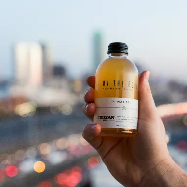 OTR Mai Tai Cocktail bottle held with city background behind