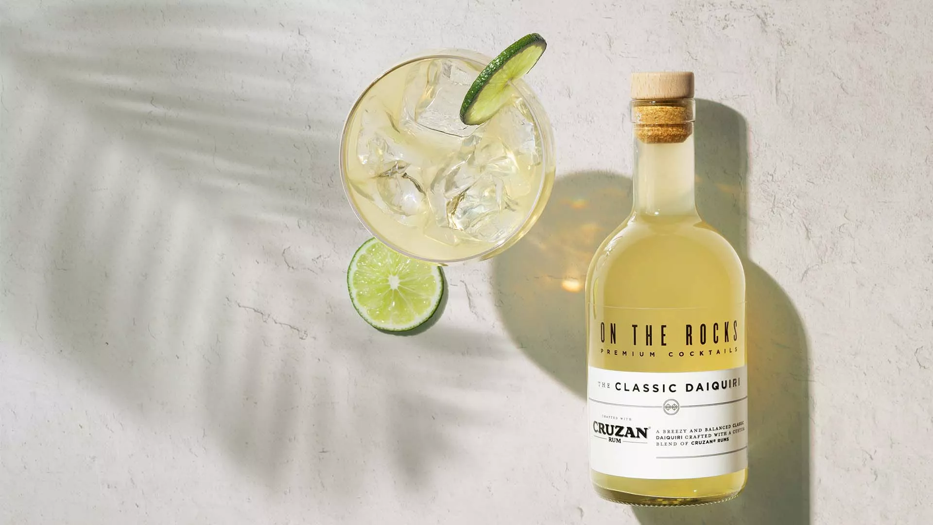 A bottle of OTR Daiquiri cocktail next to a drink served with lime