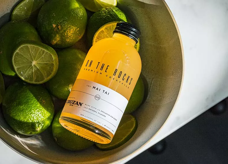 OTR Mai Tai cocktail bottle in a bowl full of limes