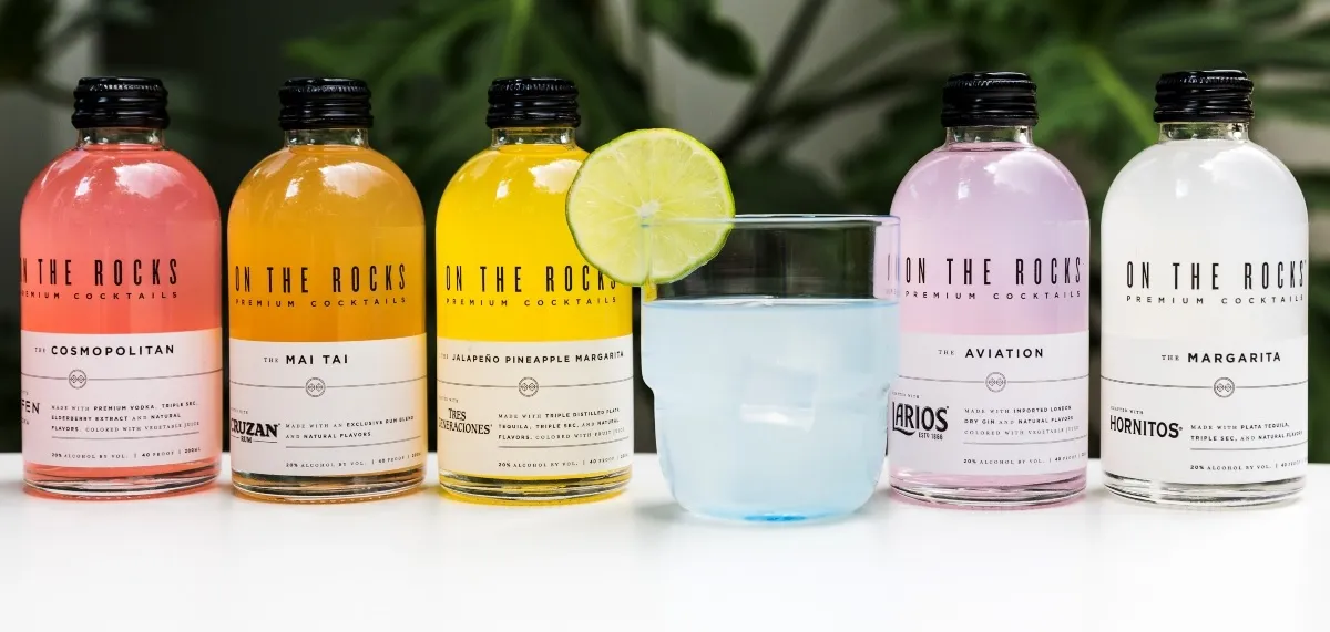 OTR premixed cocktails bottles and blue cocktail serve with lime against greenery background