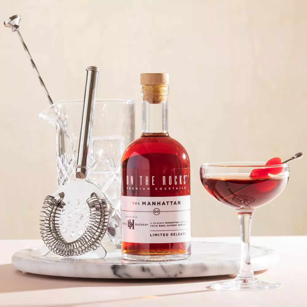 A cocktail set and a bottle and glass filled with OTR Manhattan cocktail