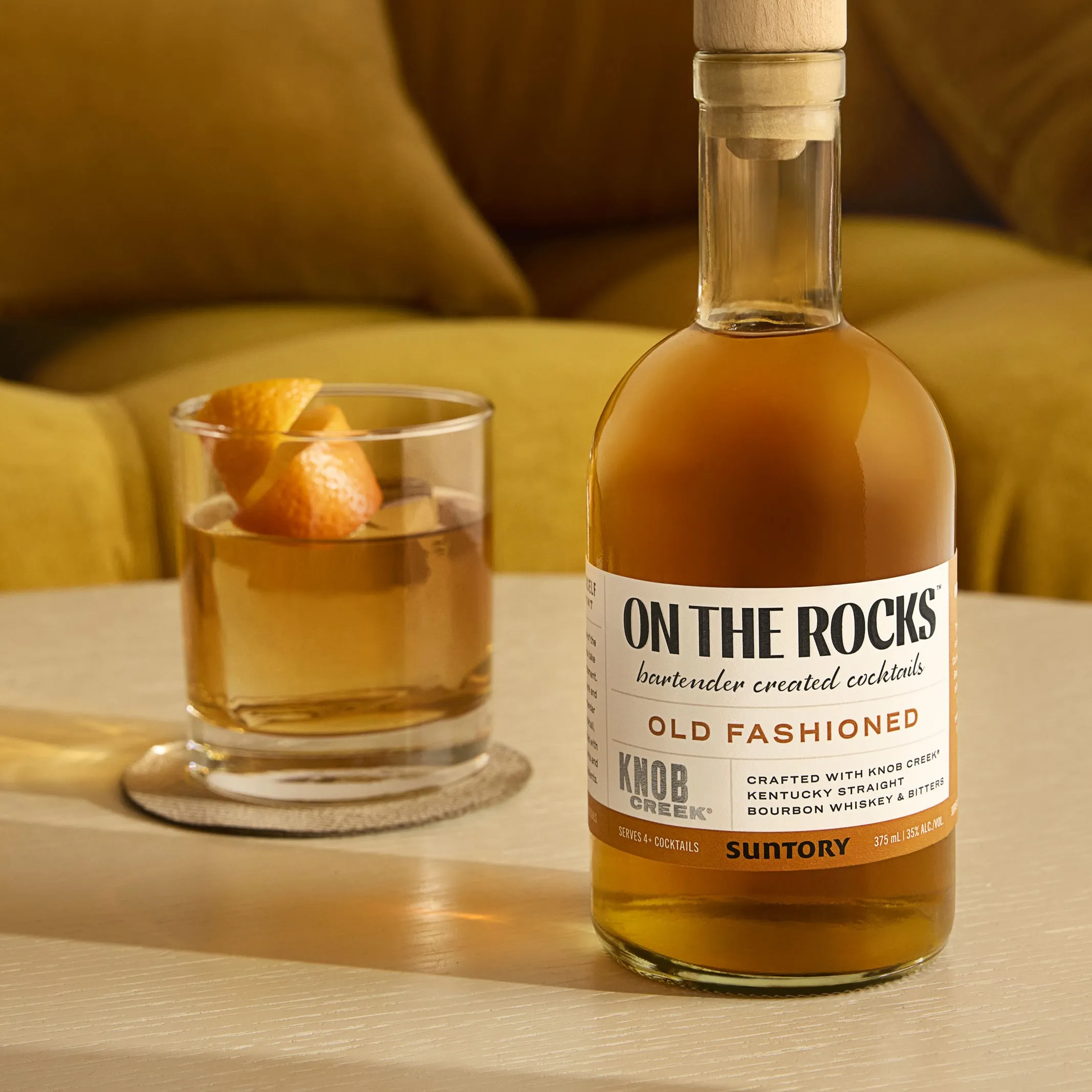 A glass of old fashioned whiskey served on the rocks, garnished with an orange twist and a cherry.