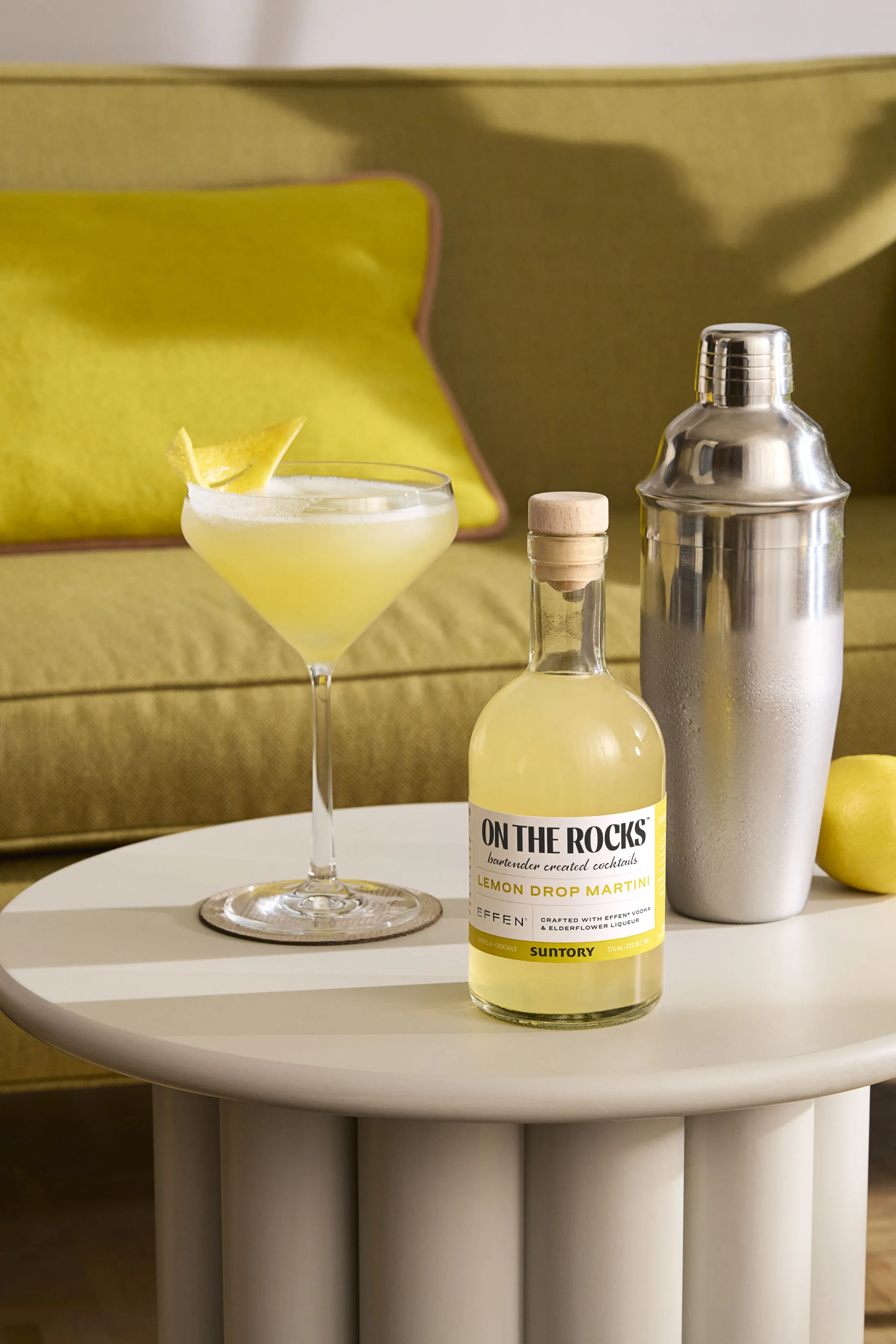 A bottle of Lemon Drop Martini and a glass of lemon drop martini garnished with peel of lemon